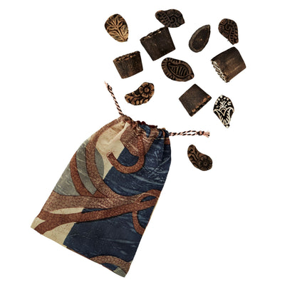 Decorative drawstring bag with patterned elements and scattered decorative items on a white background