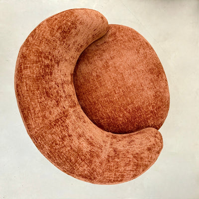 Terracotta chenille swivel armchair in a room with a wooden cabinet and plants.-Mrs Robinson