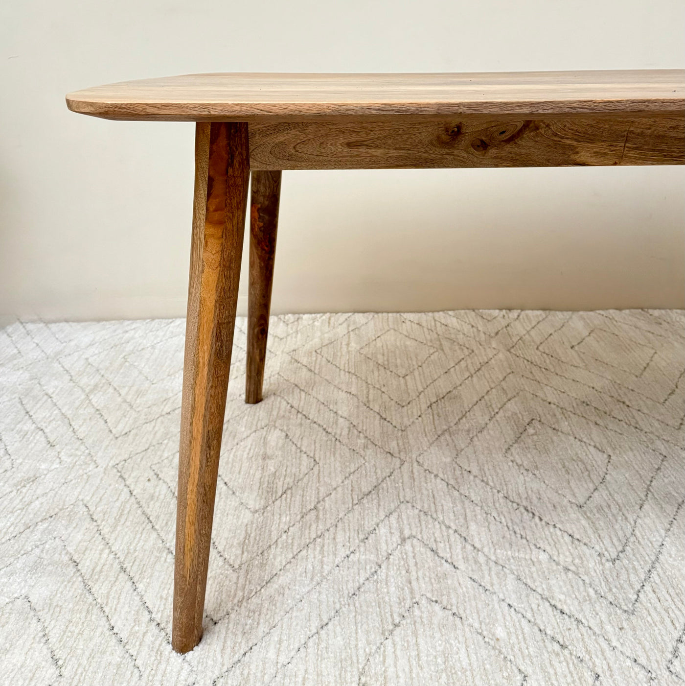 Wooden table with a single leg on a textured white rug
