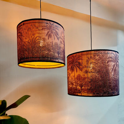 Two pendant lights with palm tree patterned shades on a neutral background