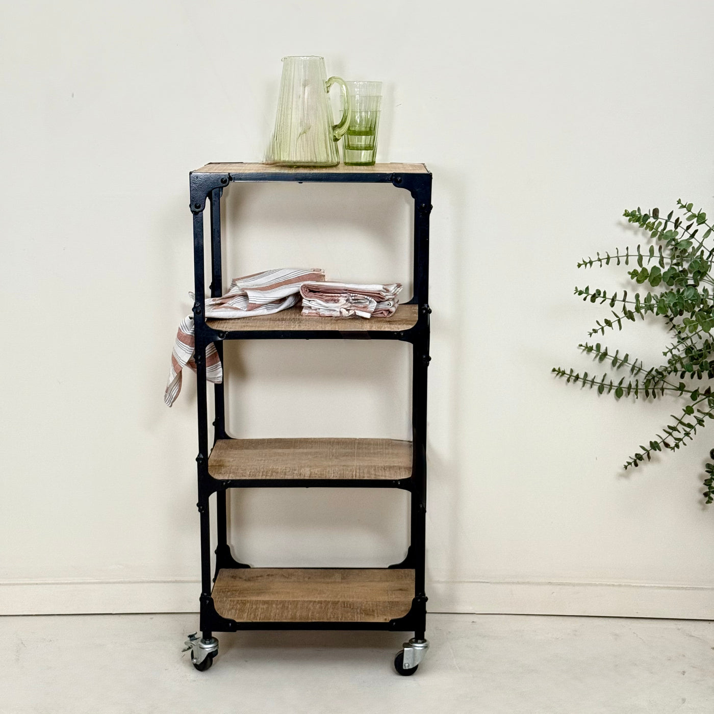 Four-tiered metal and wood shelf with a plant and glasses on a white background- Mrs Robinson