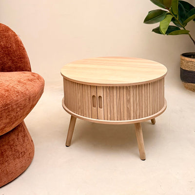 Wooden side table with a textured surface next to a brown chair on a light  Mrs Robinson floor.
