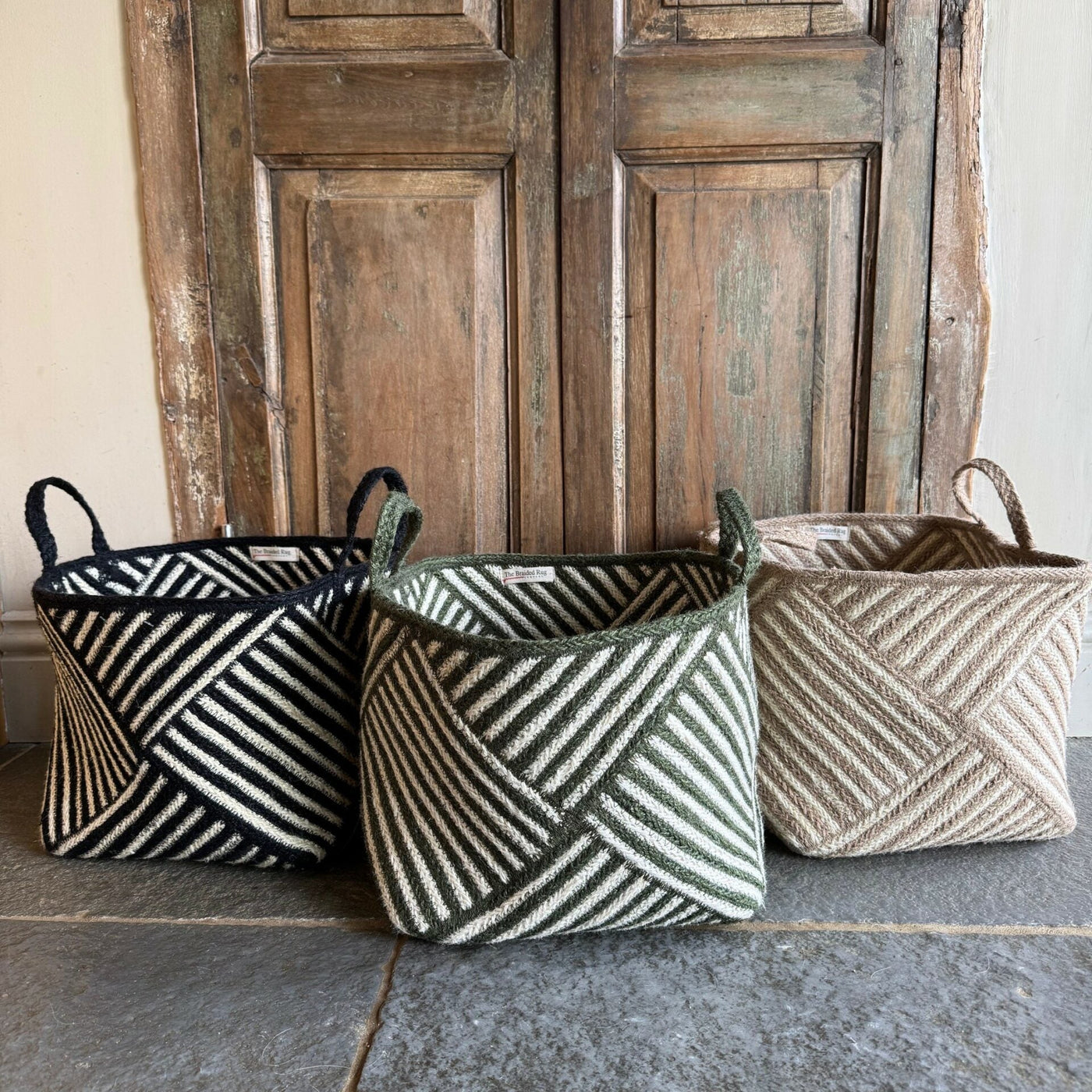 Three woven baskets with geometric patterns in front of a wooden door.