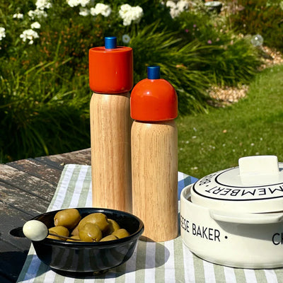 Wooden salt and pepper shakers with orange tops on a table outdoors.