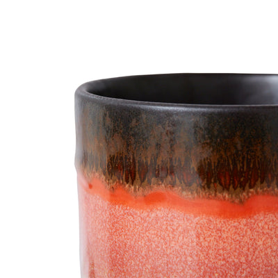 Close-up of a ceramic mug with a gradient from black to red on a white background