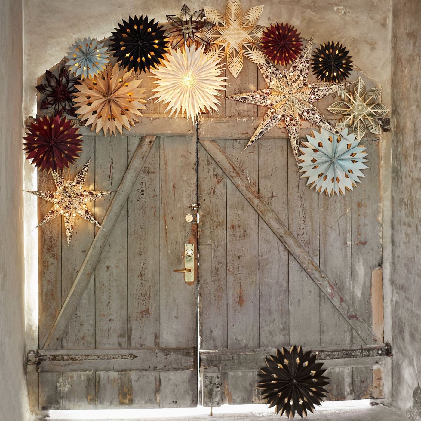 Decorative star-shaped lights on a rustic wooden door with a neutral background