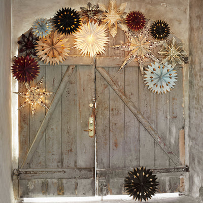 Decorative star-shaped lights on a rustic wooden door with a neutral background