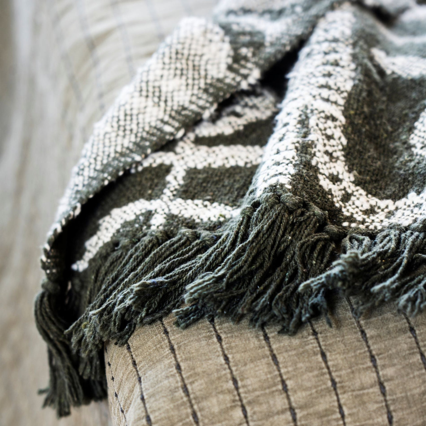Textured blanket with fringes draped over a surface