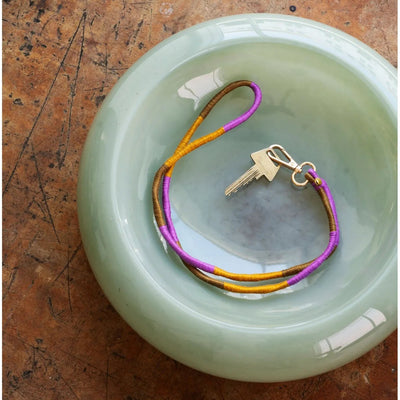 Keychain with keys on a round green glass bowl against a textured brown background