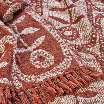 Close-up of a patterned fabric with fringes in red and beige tones.
