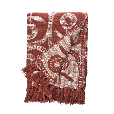Woven blanket with intricate pattern and fringes on a white background