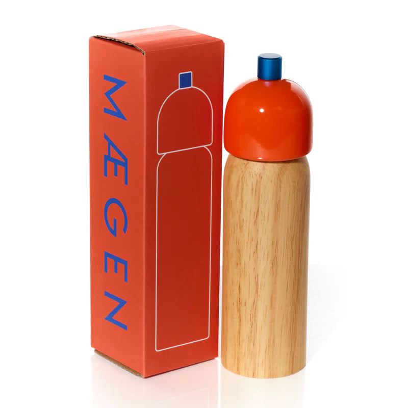 Red bottle with wooden base and blue cap next to its packaging on a white background