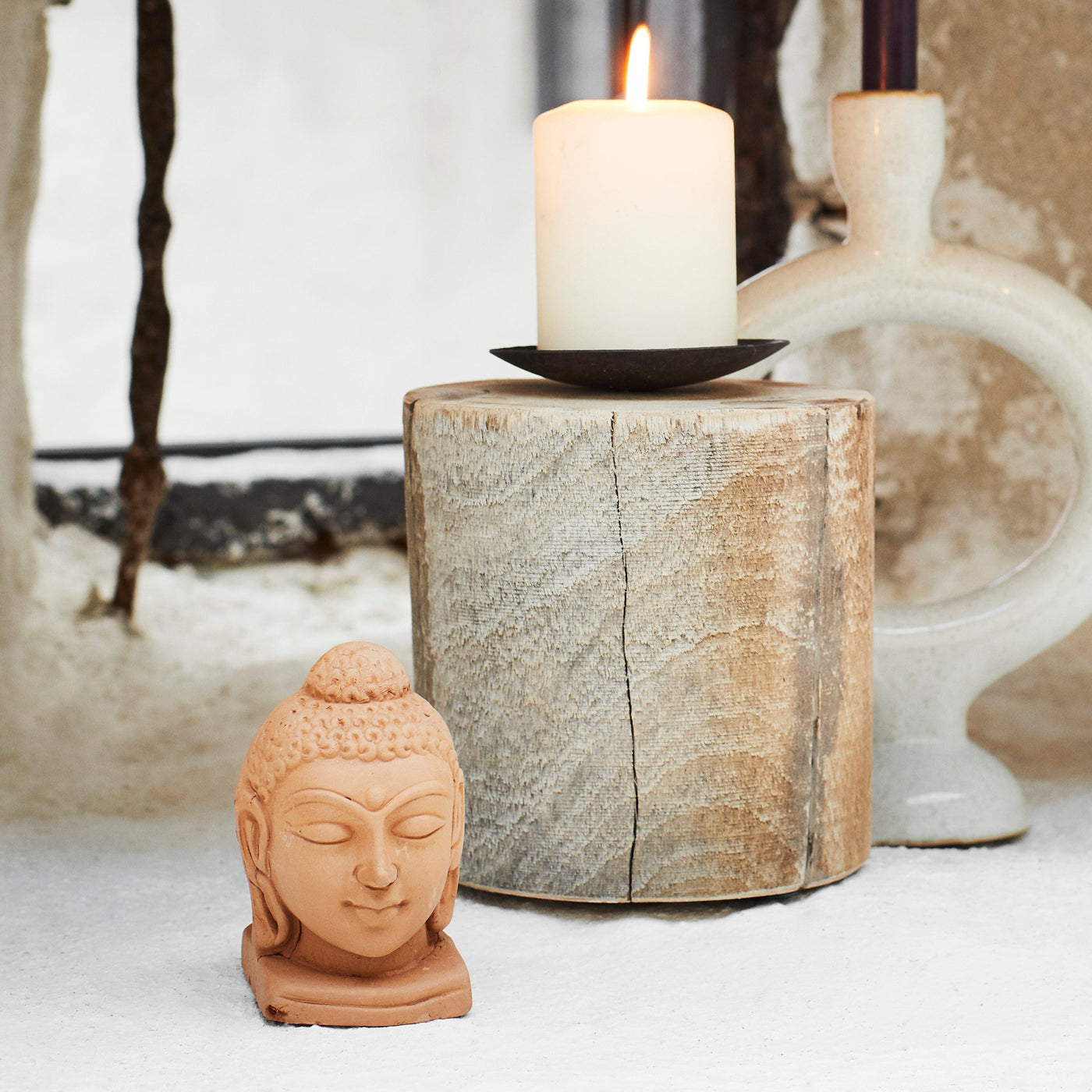 Candles in decorative holders with a Buddha statue on a rustic background
